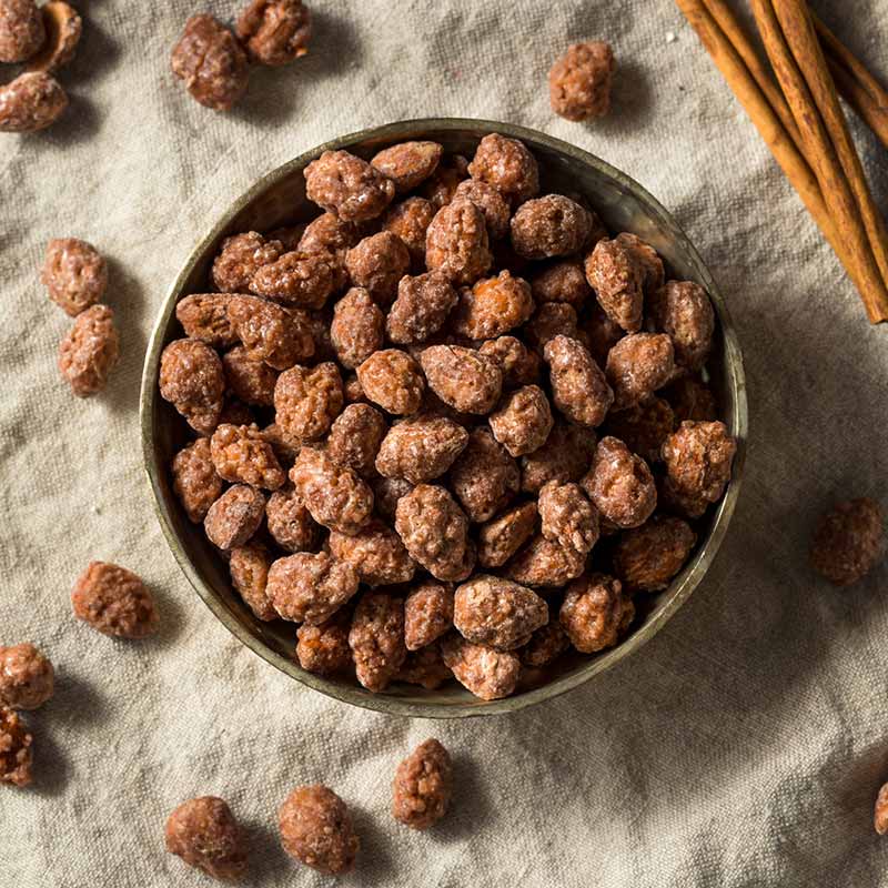 Tazón de almendras caramelizadas con palitos de canela.