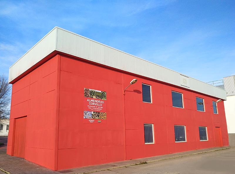 Edificio rojo con letrero de ventas de almendras.