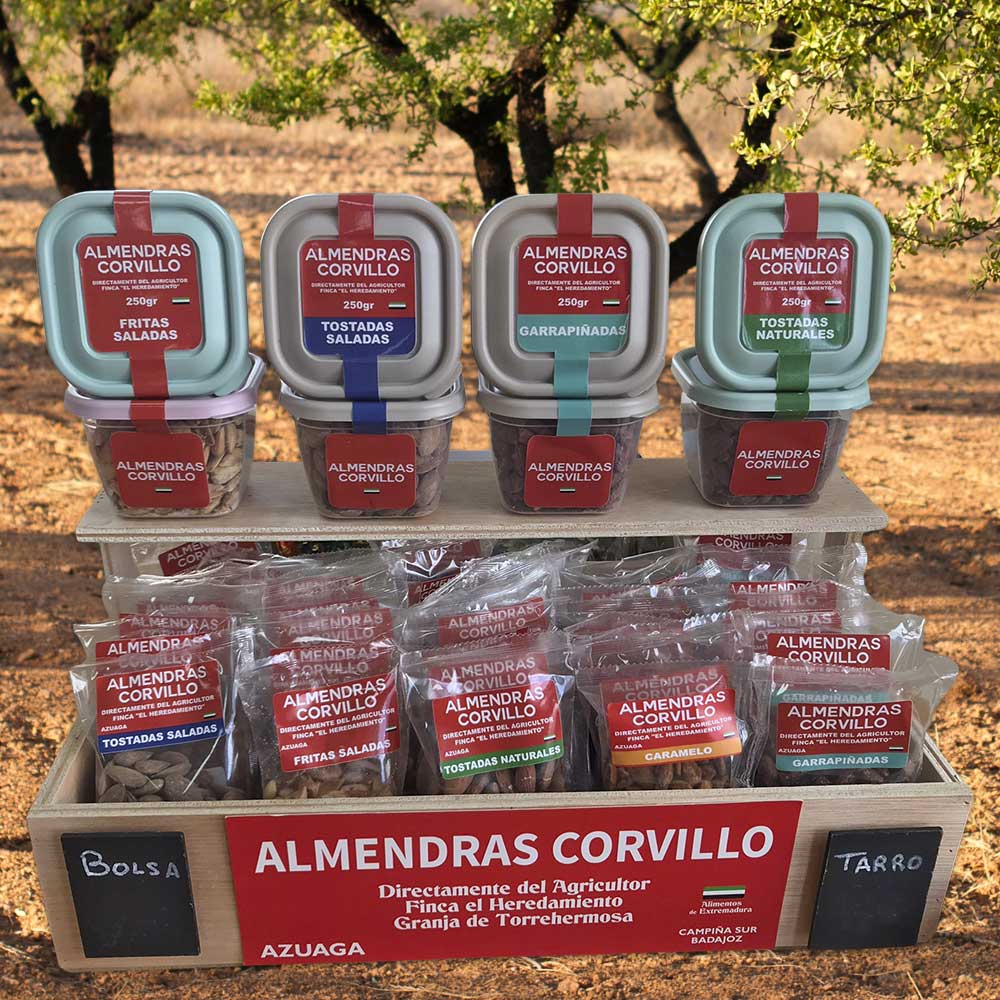 Caja de madera con diferentes tipos de almendras en un fondo de arboles.